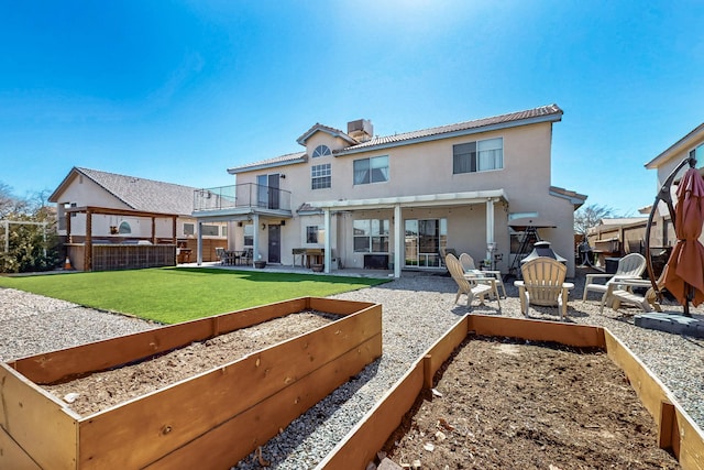 back of house featuring stucco siding, a patio, a yard, a balcony, and a chimney