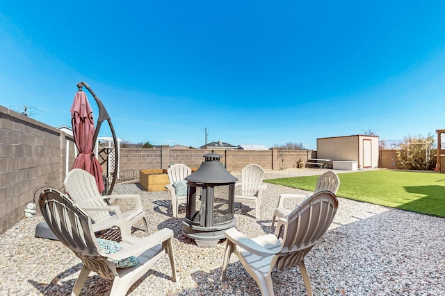 view of patio / terrace featuring an outdoor structure, a storage unit, a fenced backyard, and a fire pit