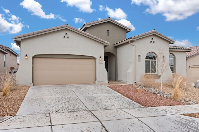 mediterranean / spanish house featuring a tile roof, concrete driveway, an attached garage, and stucco siding
