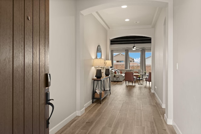 hallway featuring recessed lighting, baseboards, arched walkways, and wood finished floors