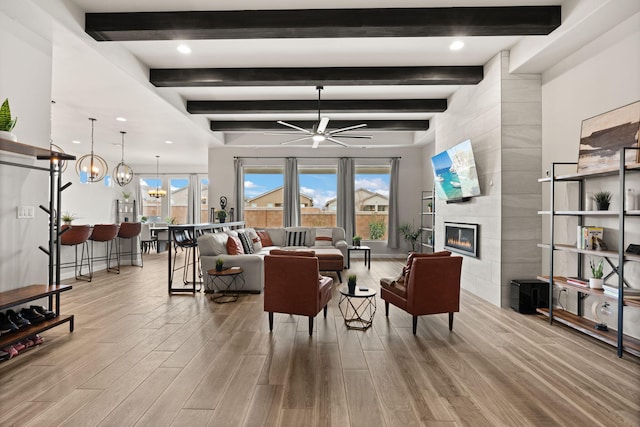 living room with wood finished floors, a ceiling fan, and a tiled fireplace