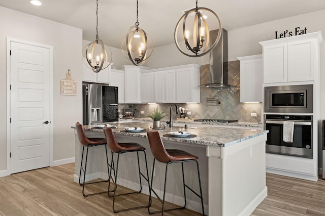 kitchen featuring a sink, an inviting chandelier, appliances with stainless steel finishes, and wall chimney range hood