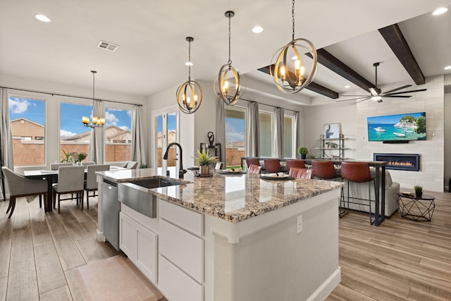 kitchen with a tiled fireplace, visible vents, wood tiled floor, a sink, and dishwasher