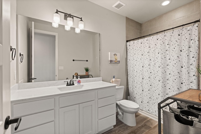 full bath with visible vents, curtained shower, toilet, wood finished floors, and vanity