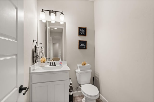 half bath with vanity, toilet, and baseboards