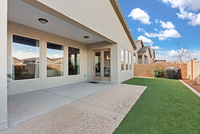 back of property featuring fence, stucco siding, a yard, and a patio area