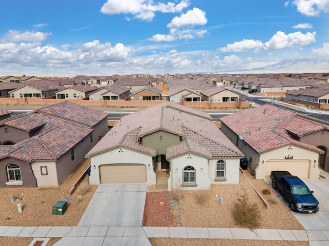view of front facade featuring concrete driveway, a residential view, a tiled roof, stucco siding, and a garage