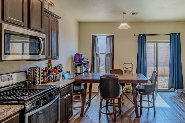 kitchen with visible vents, dark brown cabinets, stainless steel appliances, and wood finished floors