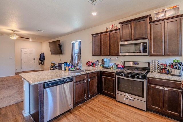 kitchen featuring visible vents, dark brown cabinets, a peninsula, stainless steel appliances, and a sink