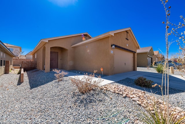 view of front of house with stucco siding, concrete driveway, an attached garage, and fence