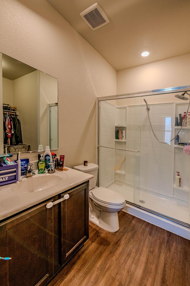 bathroom featuring visible vents, toilet, a stall shower, wood finished floors, and vanity