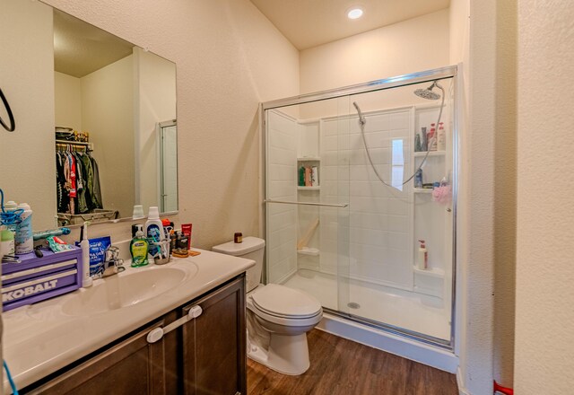 full bathroom featuring toilet, a stall shower, wood finished floors, vanity, and a textured wall