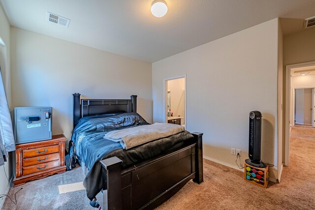 carpeted bedroom with visible vents and ensuite bath