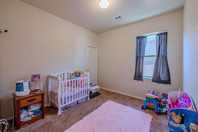 bedroom with a nursery area, carpet flooring, baseboards, and visible vents