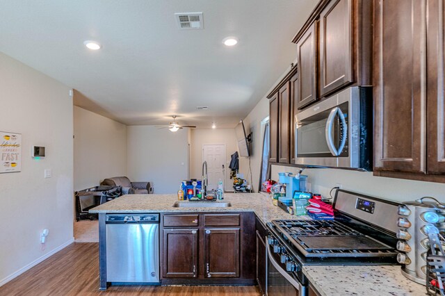 kitchen with visible vents, a sink, dark brown cabinetry, appliances with stainless steel finishes, and a peninsula