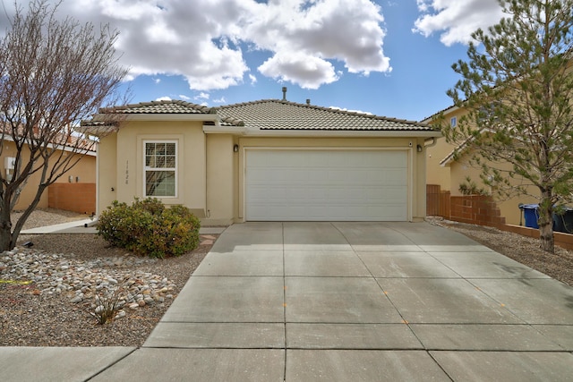 view of front of property featuring concrete driveway, a tiled roof, a garage, and stucco siding