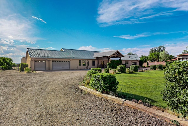 view of front of house featuring stucco siding, an attached garage, metal roof, and dirt driveway