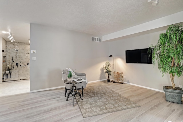 sitting room featuring baseboards, wood finished floors, visible vents, and a textured ceiling