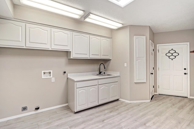 clothes washing area with light wood-style flooring, a sink, cabinet space, baseboards, and hookup for a washing machine