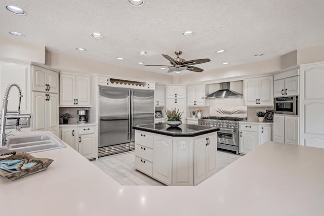 kitchen featuring premium appliances, white cabinets, and wall chimney range hood