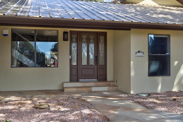 property entrance with stucco siding and metal roof