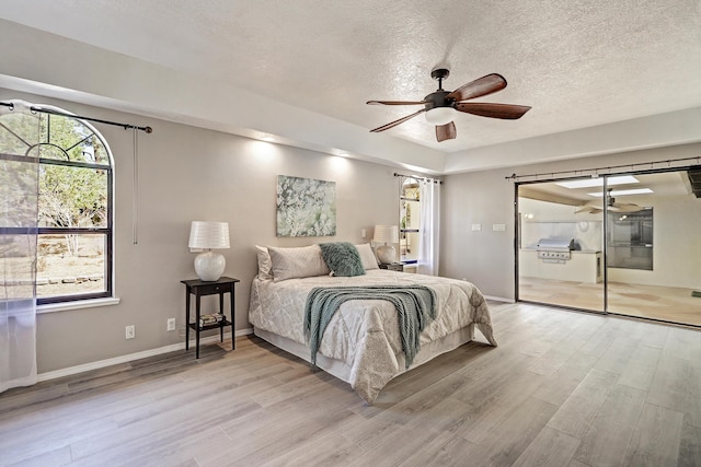 bedroom with light wood-style flooring, a textured ceiling, baseboards, and access to outside