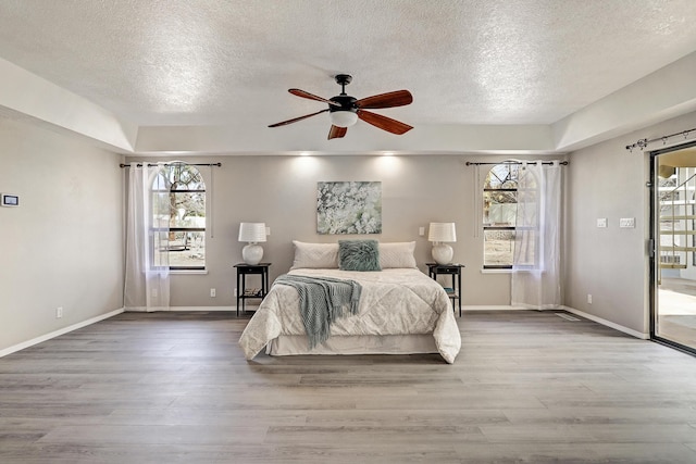 bedroom featuring baseboards, a textured ceiling, and wood finished floors