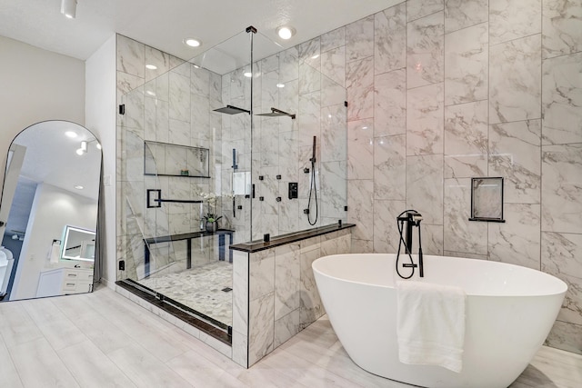 bathroom with recessed lighting, a shower stall, a freestanding bath, and tile walls