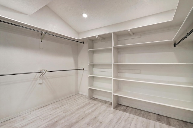 spacious closet with lofted ceiling and light wood-style floors