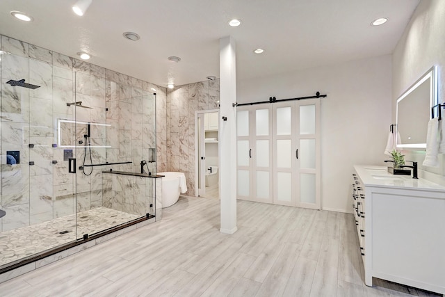 full bath with wood finished floors, recessed lighting, a shower stall, a freestanding bath, and vanity