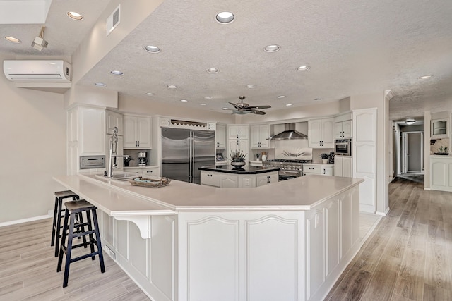 kitchen featuring visible vents, an AC wall unit, wall chimney exhaust hood, premium appliances, and a center island