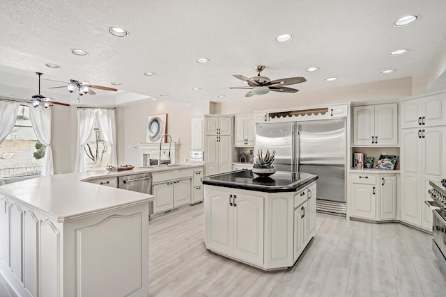 kitchen featuring high end appliances, a spacious island, a sink, light wood-style floors, and a textured ceiling