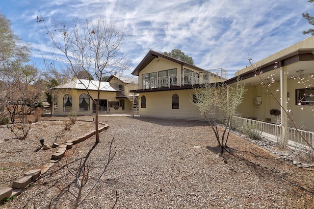 rear view of house with a balcony and stucco siding