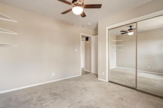 unfurnished bedroom with baseboards, carpet floors, ceiling fan, a closet, and a textured ceiling