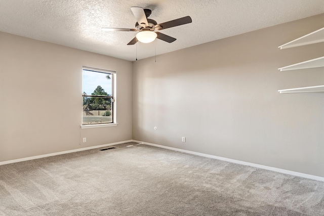 carpeted empty room featuring visible vents, ceiling fan, a textured ceiling, and baseboards