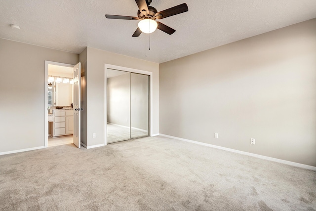 unfurnished bedroom featuring carpet, baseboards, a closet, a textured ceiling, and connected bathroom