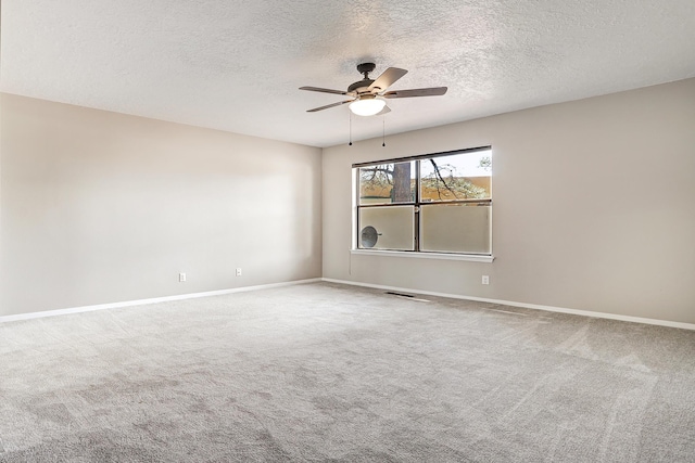 carpeted spare room with a ceiling fan, baseboards, and a textured ceiling