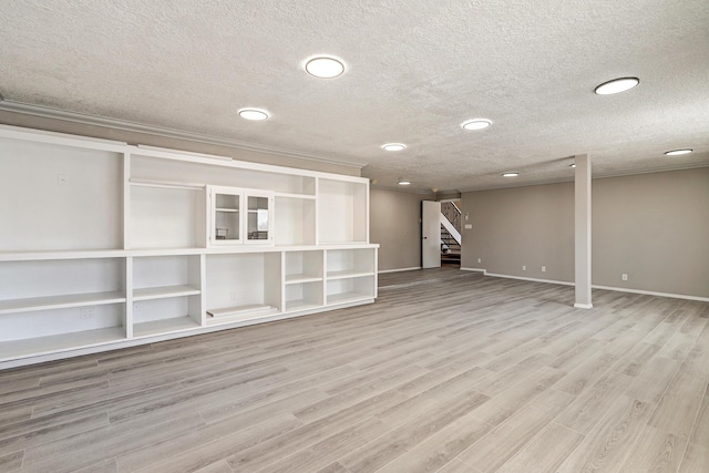 below grade area featuring stairs, light wood-style floors, baseboards, and a textured ceiling