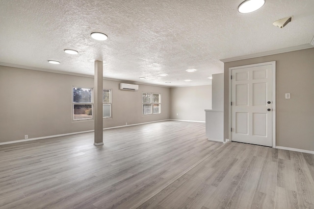 interior space featuring light wood-style flooring, a wall mounted air conditioner, crown molding, and baseboards