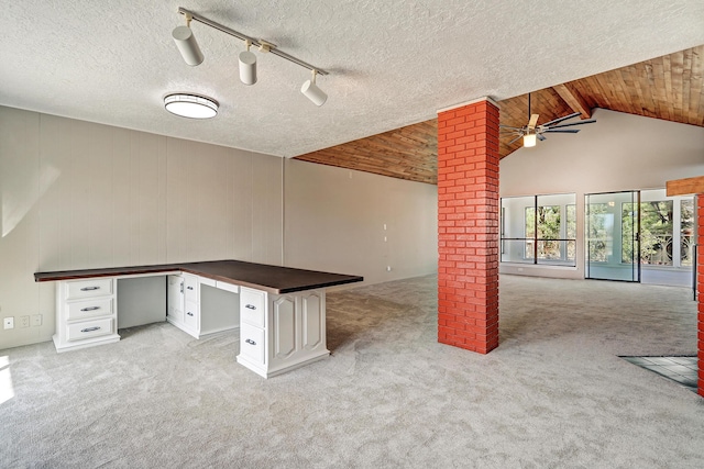 unfurnished office with light carpet, built in desk, rail lighting, a textured ceiling, and a ceiling fan