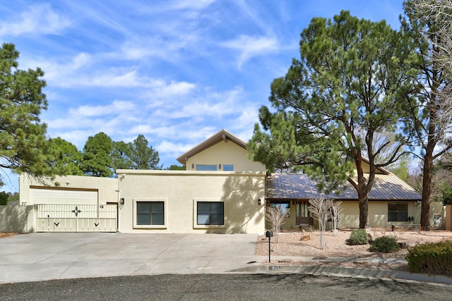 view of front of house with a gate, driveway, and stucco siding