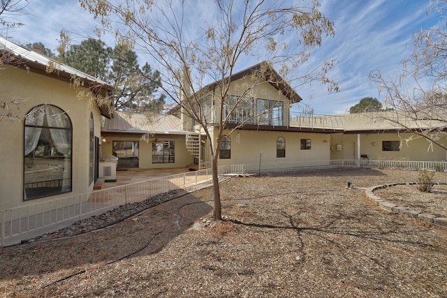 back of property featuring stucco siding, fence, metal roof, stairs, and a patio area