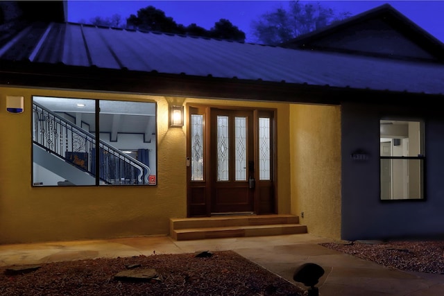 doorway to property with stucco siding, french doors, and metal roof