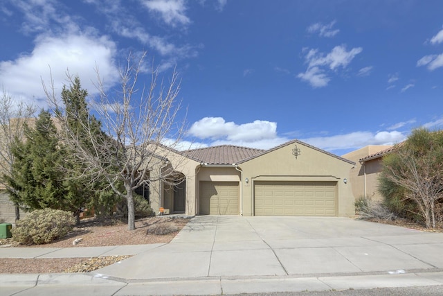 mediterranean / spanish house with stucco siding, driveway, a tile roof, and a garage