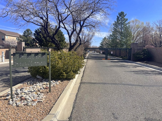 view of road featuring a gate, curbs, and a gated entry