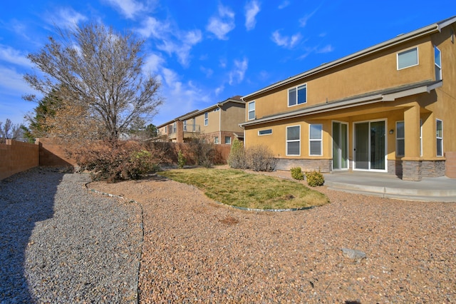 back of house with fence, a patio area, stone siding, and stucco siding