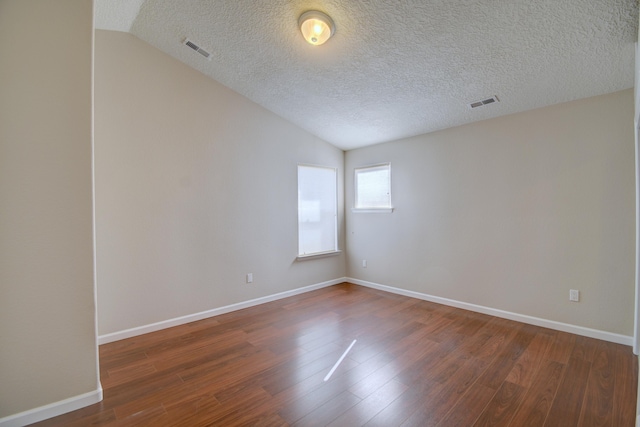 unfurnished room with dark wood finished floors, visible vents, baseboards, and lofted ceiling