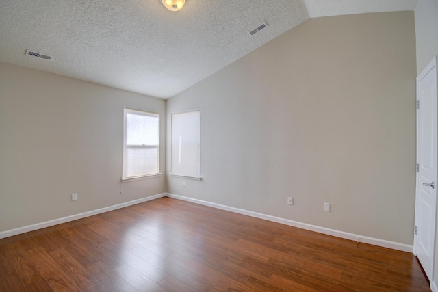 spare room featuring visible vents, lofted ceiling, and wood finished floors