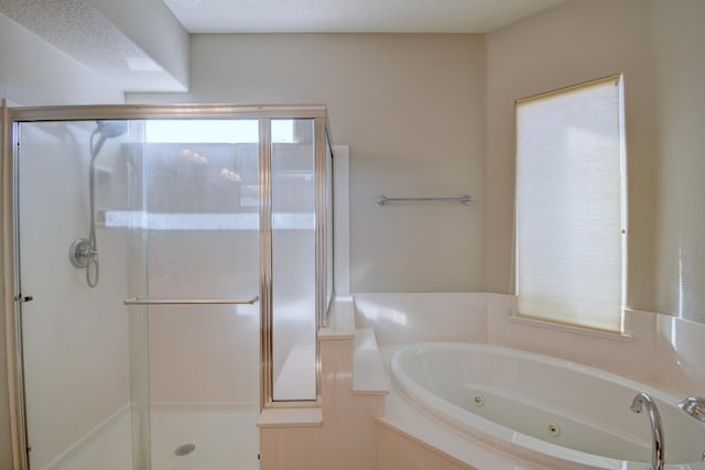 bathroom featuring a textured ceiling, a stall shower, and a whirlpool tub