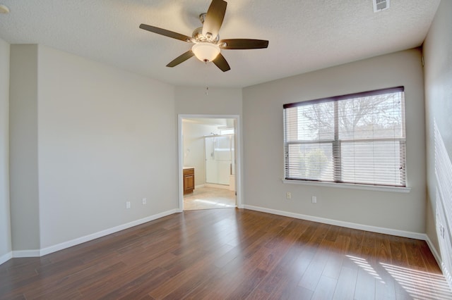 empty room featuring ceiling fan, a textured ceiling, baseboards, and wood finished floors